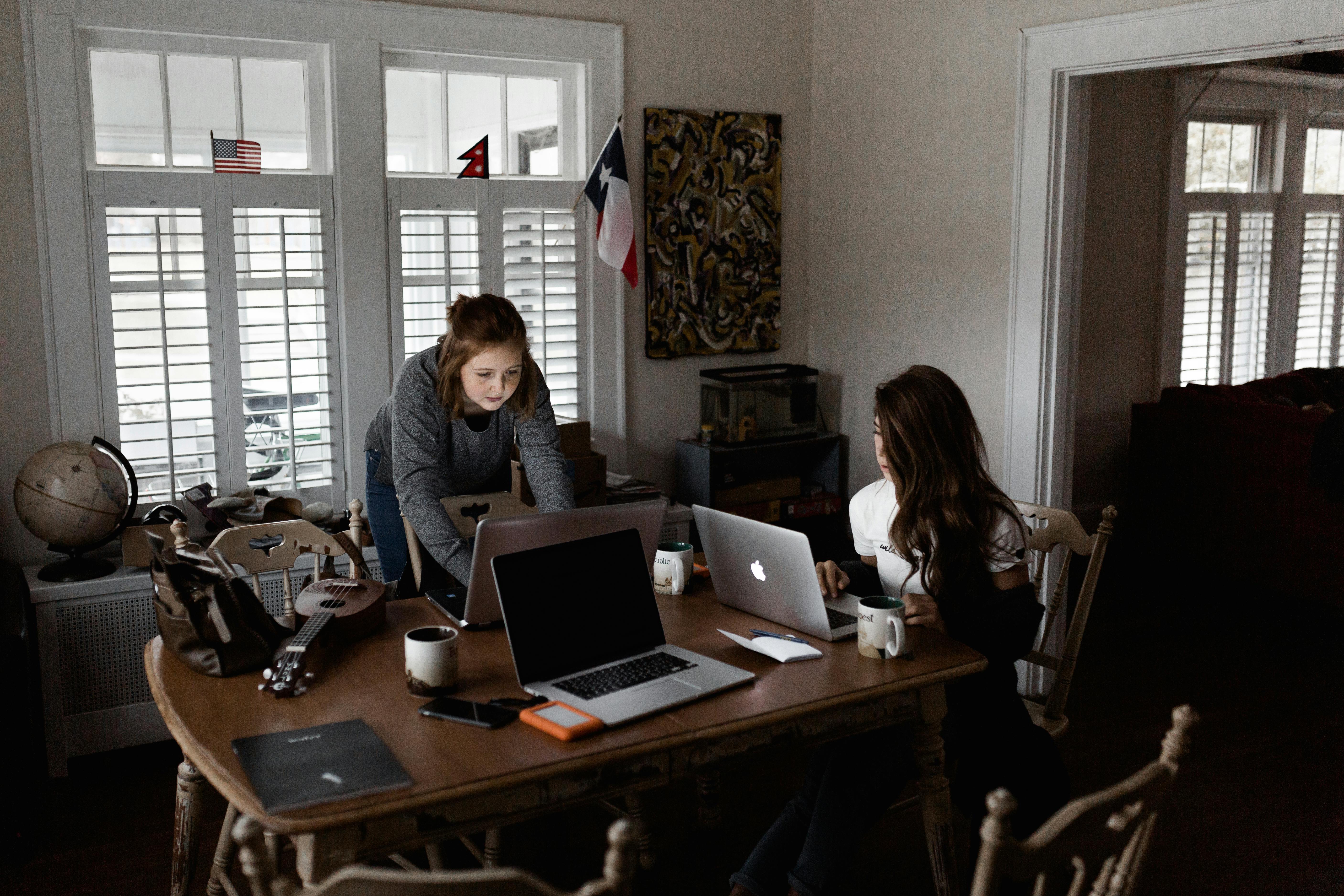 Two young women working collaboratively in a cozy home office setting.